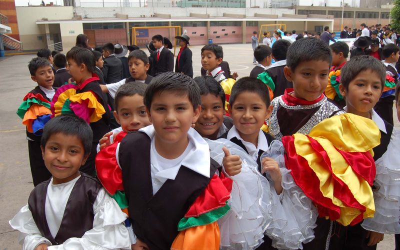 Niños de primaria sonrientes con trajes típicos de colores en una danza