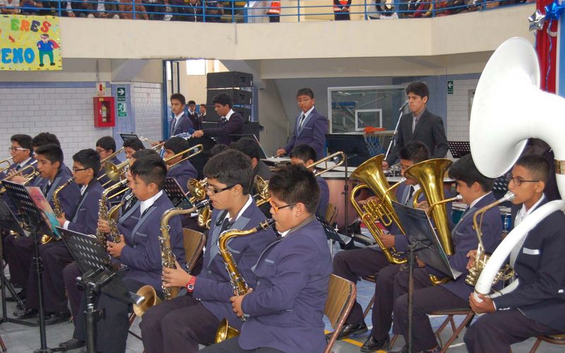 Banda escolar de secundaria tocando trompetas y saxofones en el coliseo