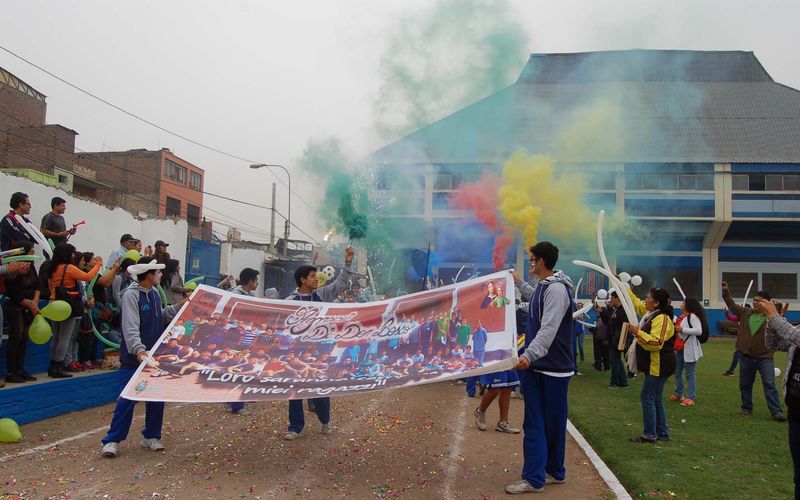 Estudiantes celebrando con humo de colores y pancarta en el patio