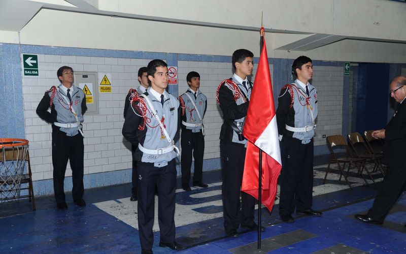 Escolta de estudiantes con la bandera del Perú durante una ceremonia cívica