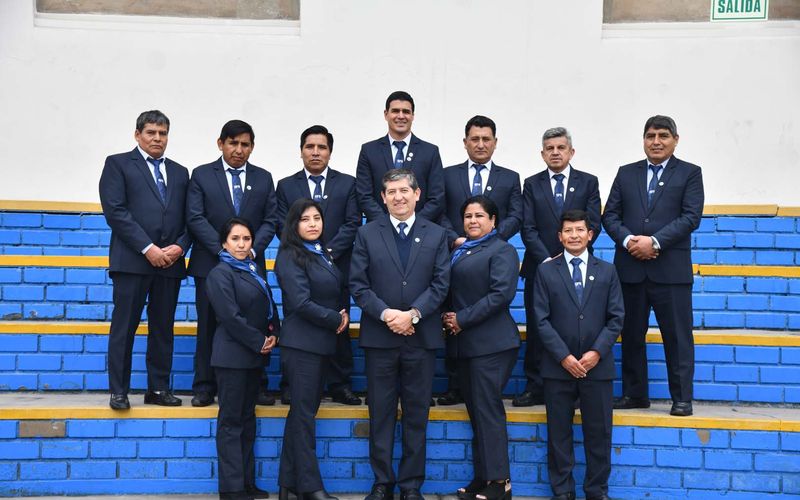 Equipo docente con ropa formal posando sobre una escalinata azul