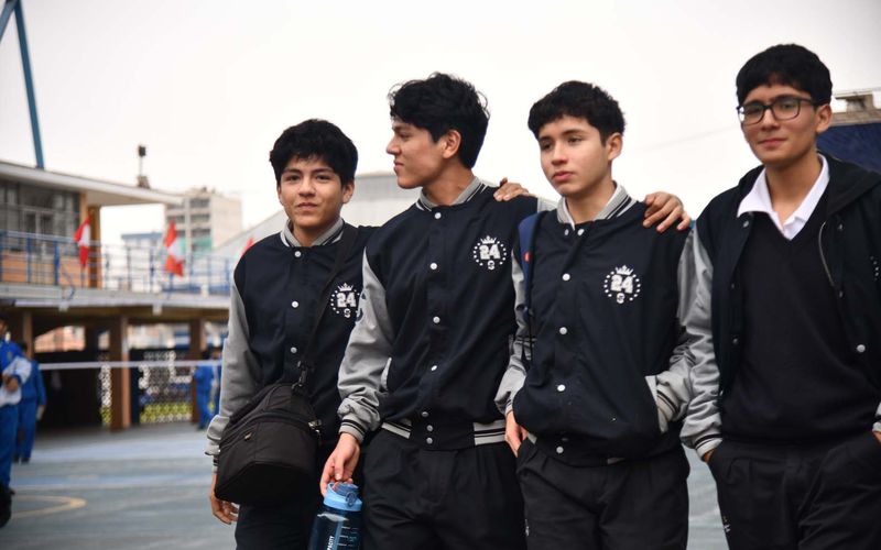Cuatro estudiantes de secundaria abrazados caminando por el patio