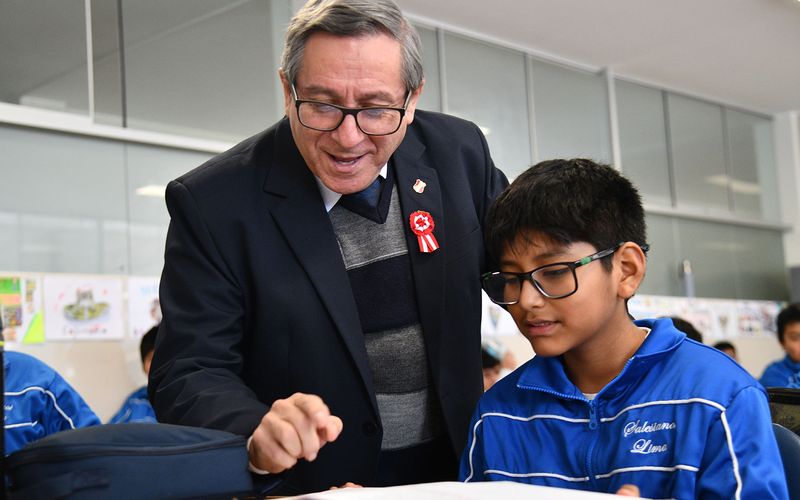 Docente conversando y explicando a un niño de primaria en el aula