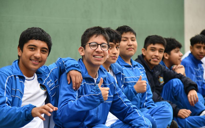 Grupo de estudiantes de secundaria sentados en el aula con el pulgar en alto