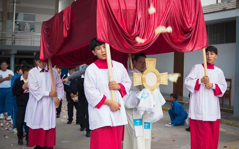 Procesión del Corpus Christi con palio rojo y acólitos con sotana