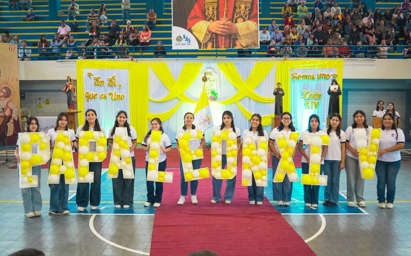 Estudiantes formando con globos amarillos las letras PAPA LEON XIV en el escenario del coliseo durante la fiesta del Papa