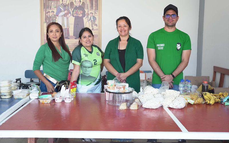 Voluntarios con polos verdes detrás de la mesa de la jornada misionera