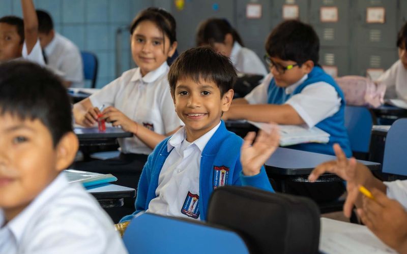 Niños de primaria sonrientes compartiendo en el aula