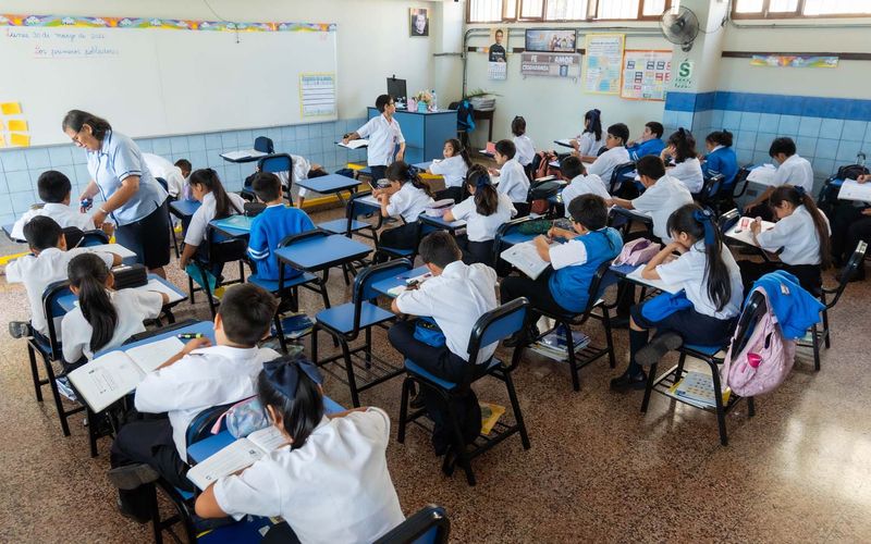 Aula de primaria llena de estudiantes trabajando en sus mesas