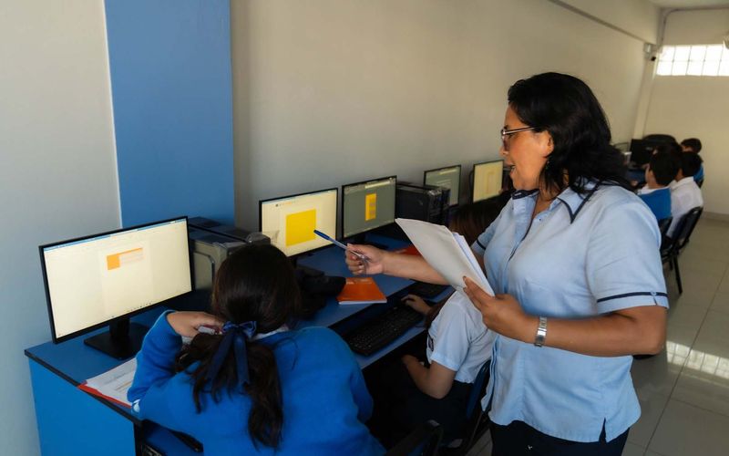 Docente guiando a estudiantes en la sala de cómputo