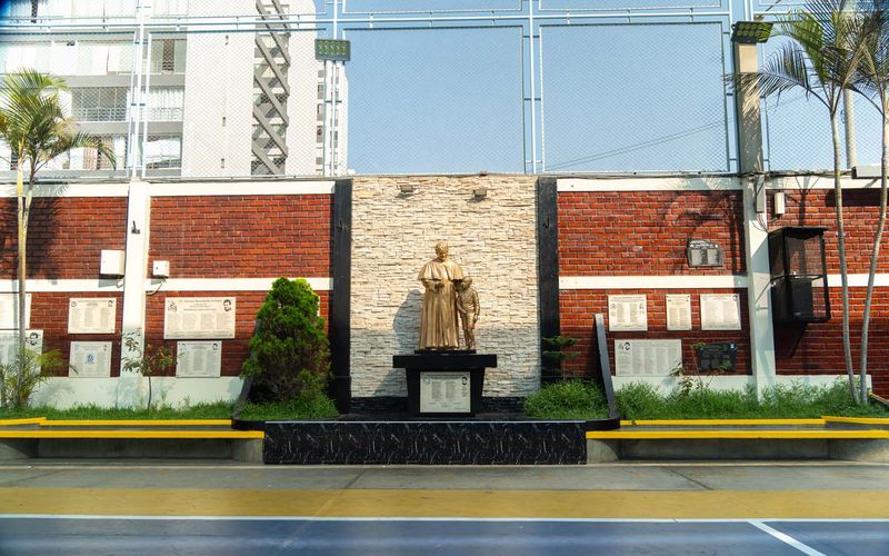 Patio con el monumento a Don Bosco y el colegio al fondo