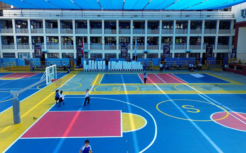 Patio deportivo de colores con arco de fútbol y pabellón de aulas