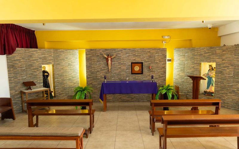 Capilla de la escuela con altar, crucifijo y bancas de madera