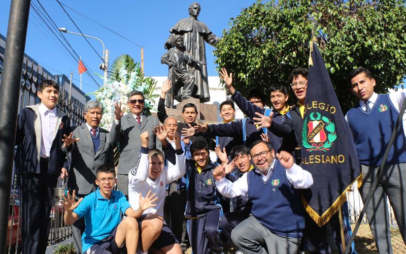 Estudiantes con la bandera junto al monumento a Don Bosco