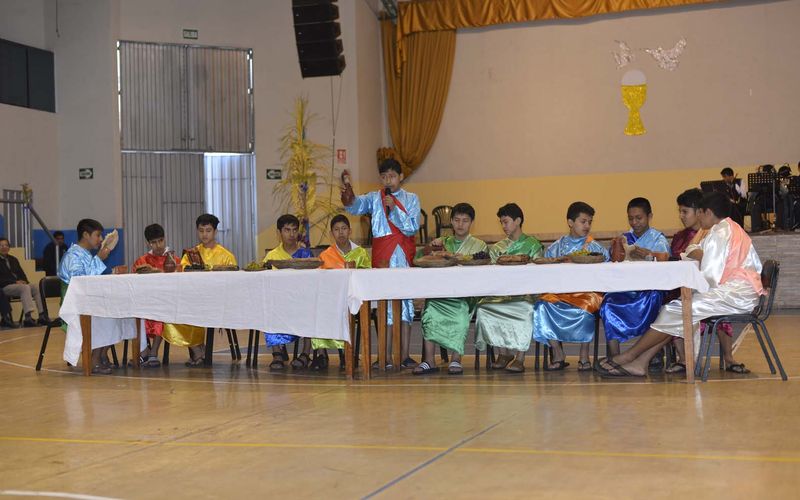 Alumnos con vestuario bíblico representando la Última Cena en el coliseo del colegio