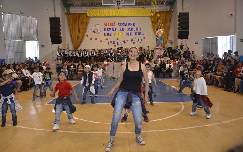 Una madre baila con niños de primaria en el coliseo durante la celebración del Día de la Madre