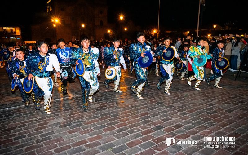 Danzantes con trajes azules y sombreros en una presentación nocturna en las calles de Cusco