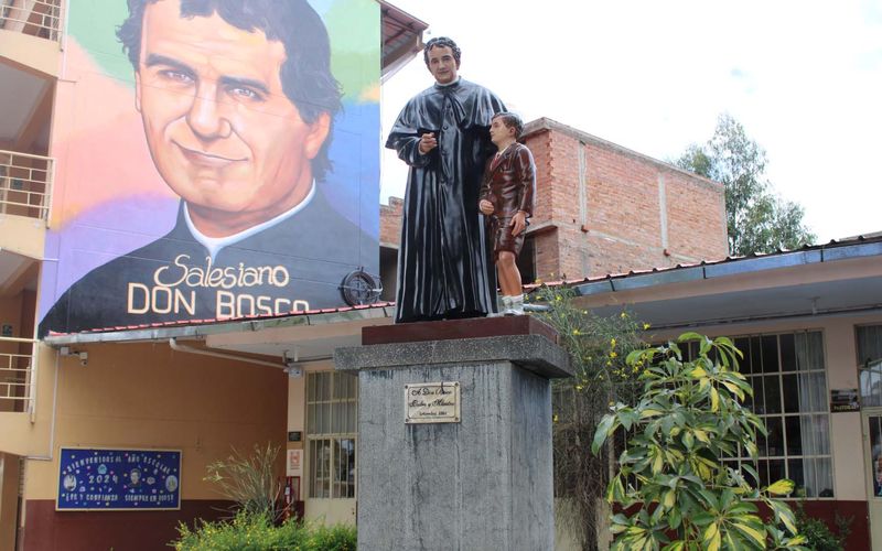 Mural gigante de Don Bosco y estatua en el patio de la escuela