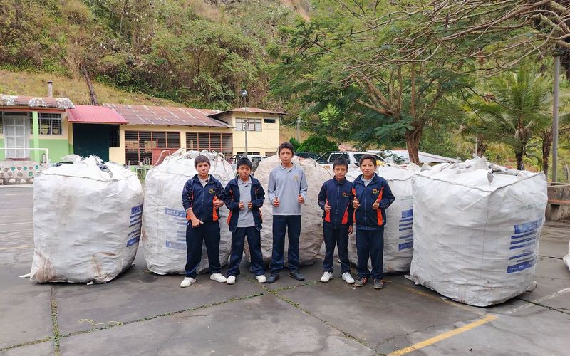 Estudiantes junto a fardos de material reciclado en un proyecto ambiental