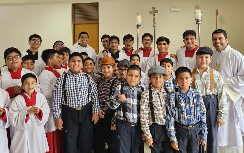 Monaguillos y alumnos posando con el sacerdote tras la misa