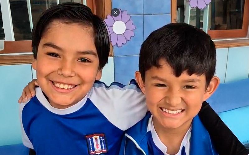 Dos niños de primaria sonriendo y abrazados en el aula
