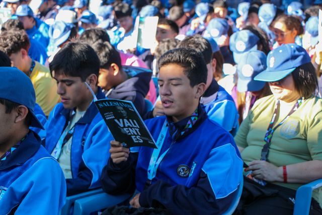 Jóvenes cantan juntos con el cuadernillo del encuentro en las manos