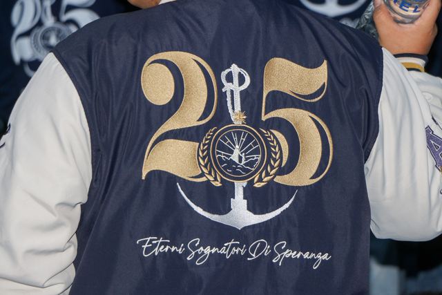 Espalda de una chaqueta de promoción con el número 25, un ancla y el lema «Eterni sognatori di speranza»