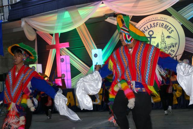 Dos bailarines con ponchos de colores durante una danza andina en el escenario