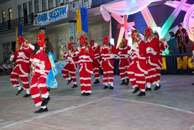 Grupo de danzantes con trajes rojos y blancos en una danza nocturna