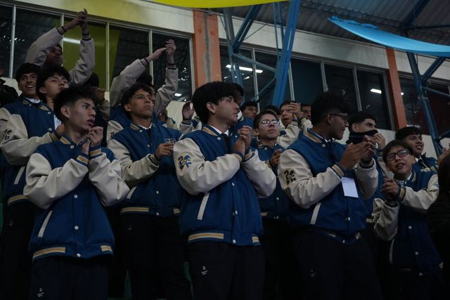 Jóvenes con chaquetas de promoción aplauden durante la inauguración del encuentro