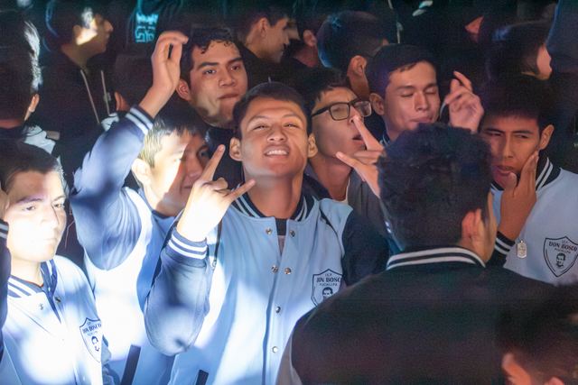 Estudiantes con chaquetas de promoción posan alegres durante la fiesta juvenil nocturna