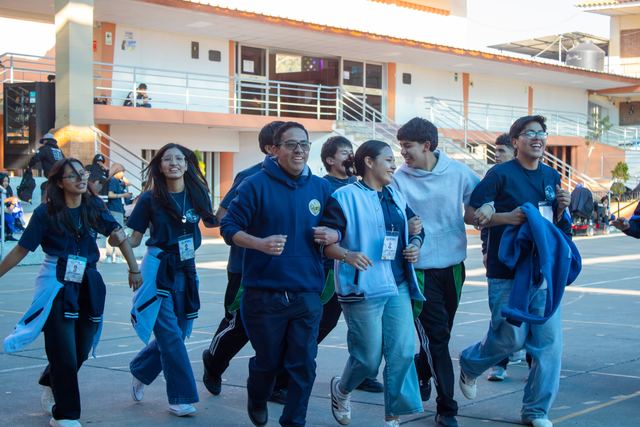 Jóvenes corren de la mano sonriendo por el patio