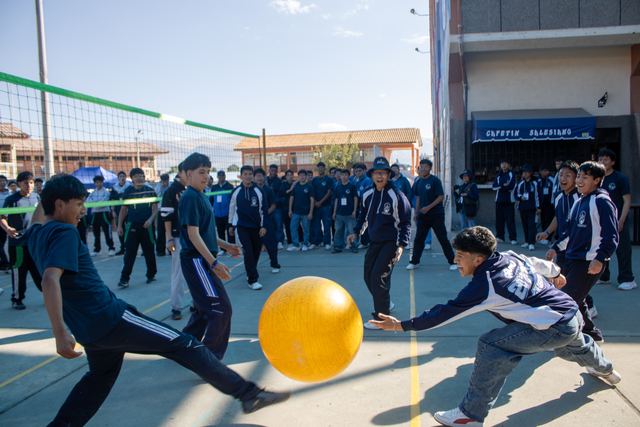 Estudiantes juegan con una pelota gigante amarilla en el patio durante los Juegos Salesianos