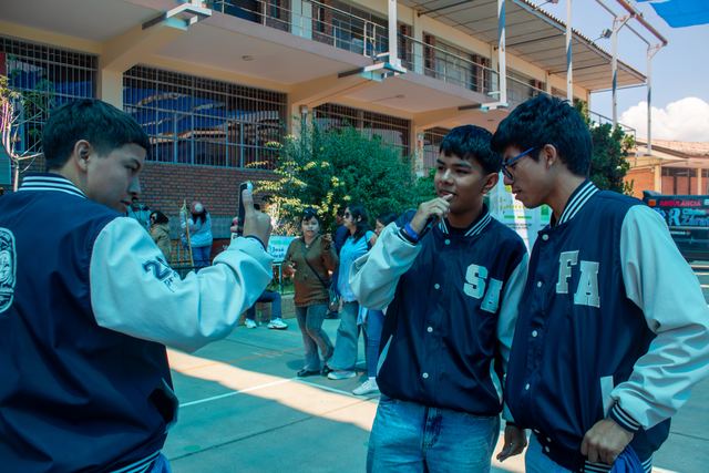 Estudiantes con chaquetas de promoción graban un video con el celular