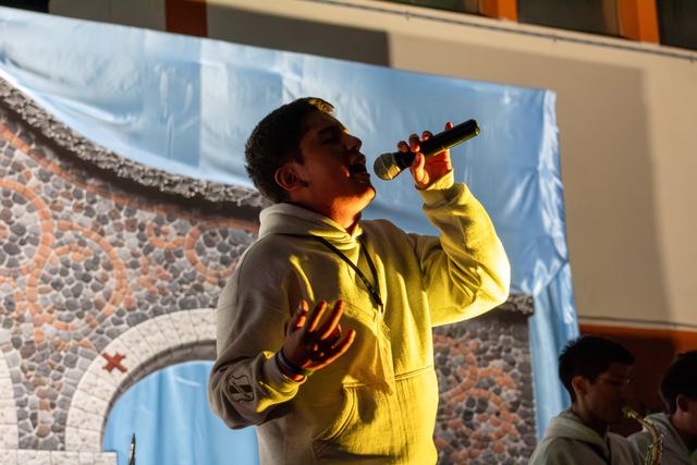 Joven canta con micrófono sobre el escenario iluminado