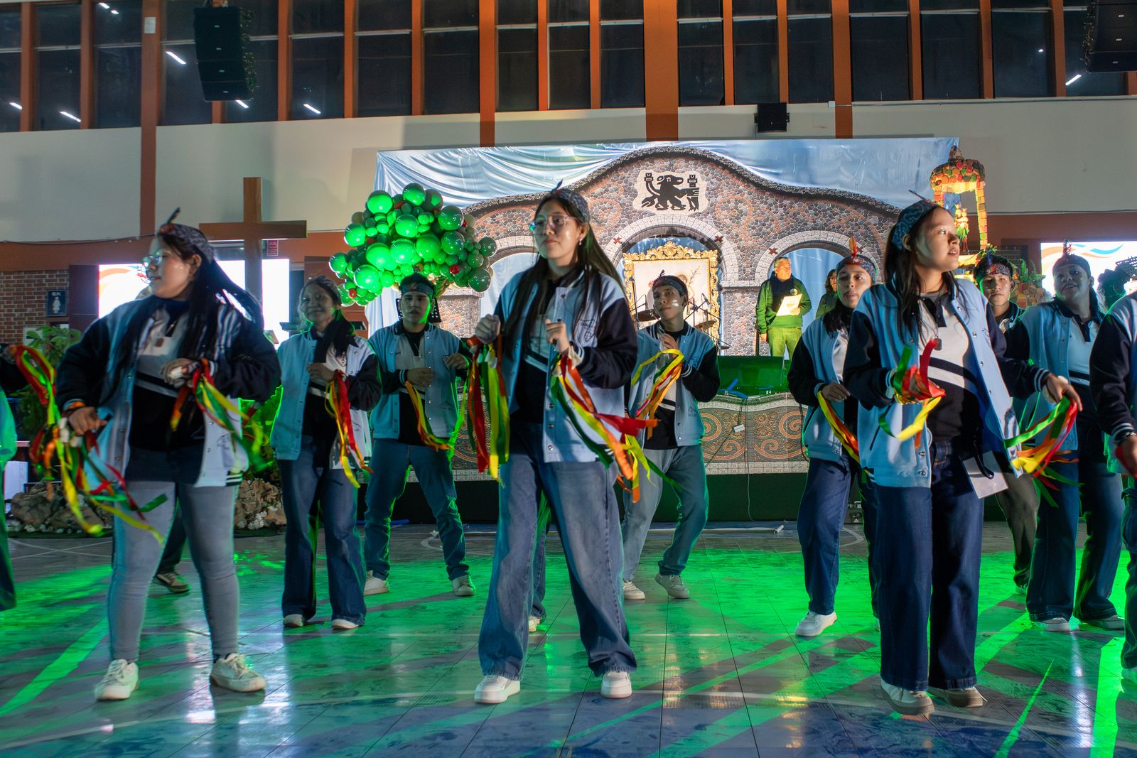 Jóvenes bailan con cintas de colores en el escenario de la Noche Cultural