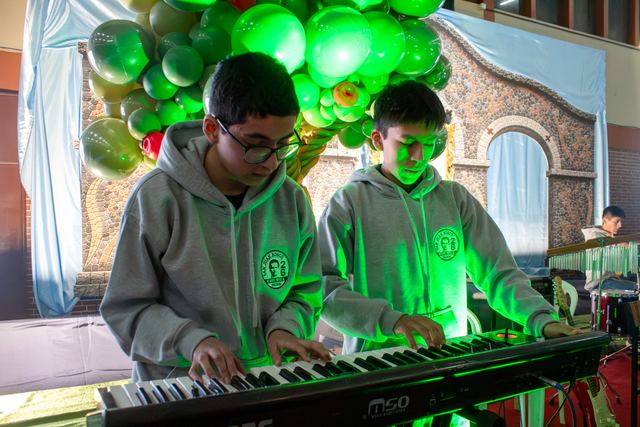 Dos estudiantes tocan un teclado bajo luces verdes