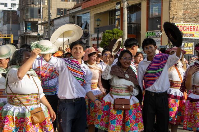 Jóvenes y adultos con trajes típicos bailan en la calle con los sombreros en alto