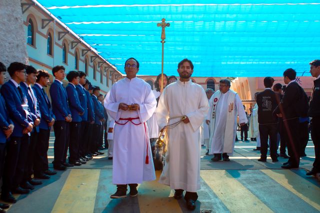 Acólitos con cruz e incienso abren la procesión entre filas de estudiantes