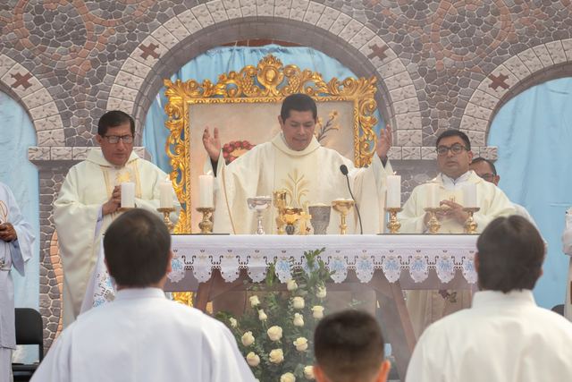 Sacerdote con los brazos abiertos frente al altar durante la Eucaristía