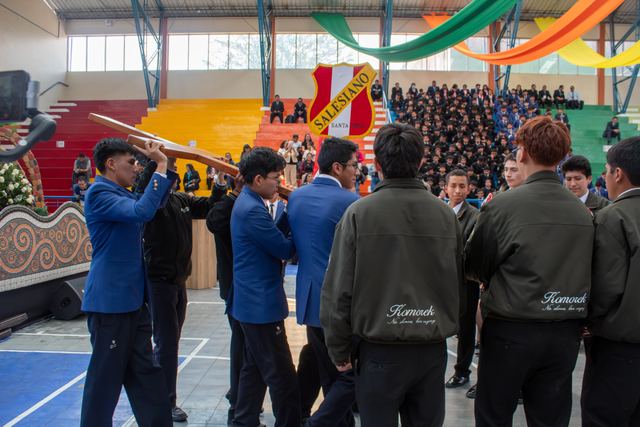 Jóvenes con chaquetas azules levantan la cruz de madera durante la entrega